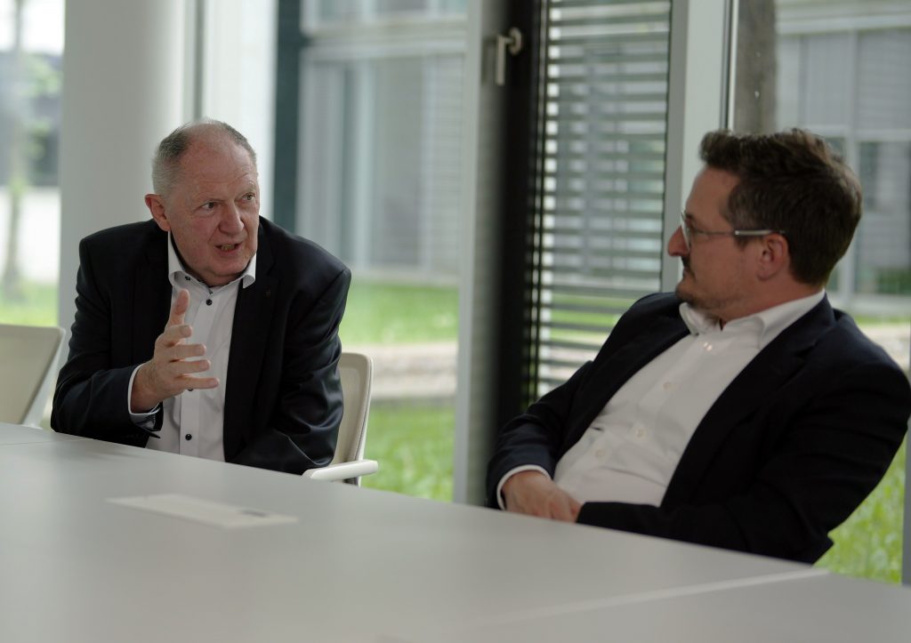 Zwei Herren an einem Tisch bei einer Unterhaltung