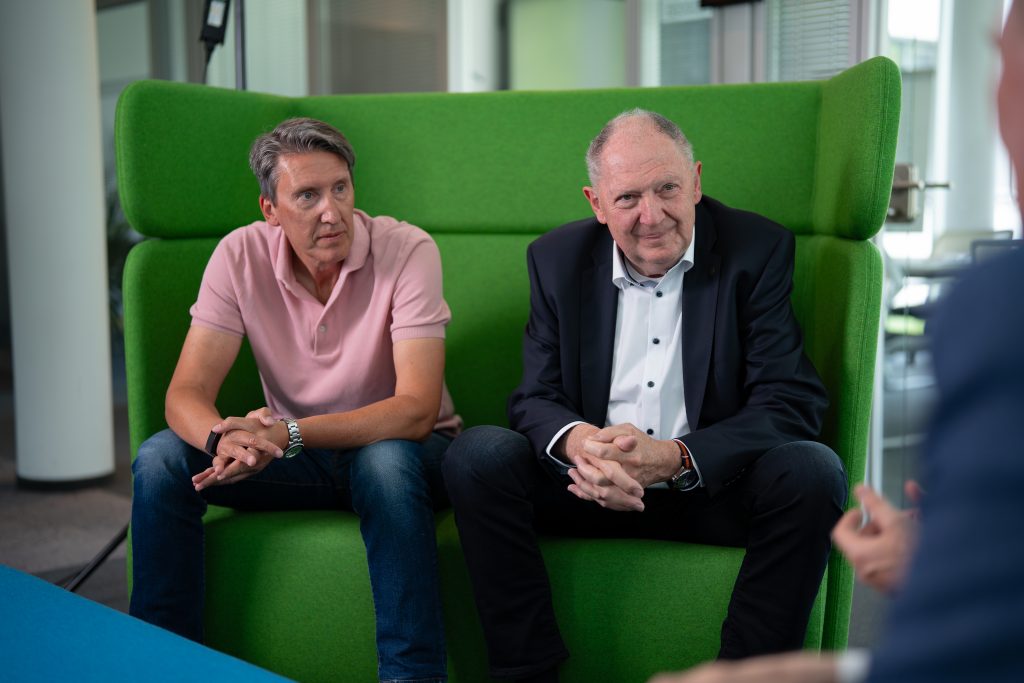 Zwei Herren sitzen auf einer grünen Couch